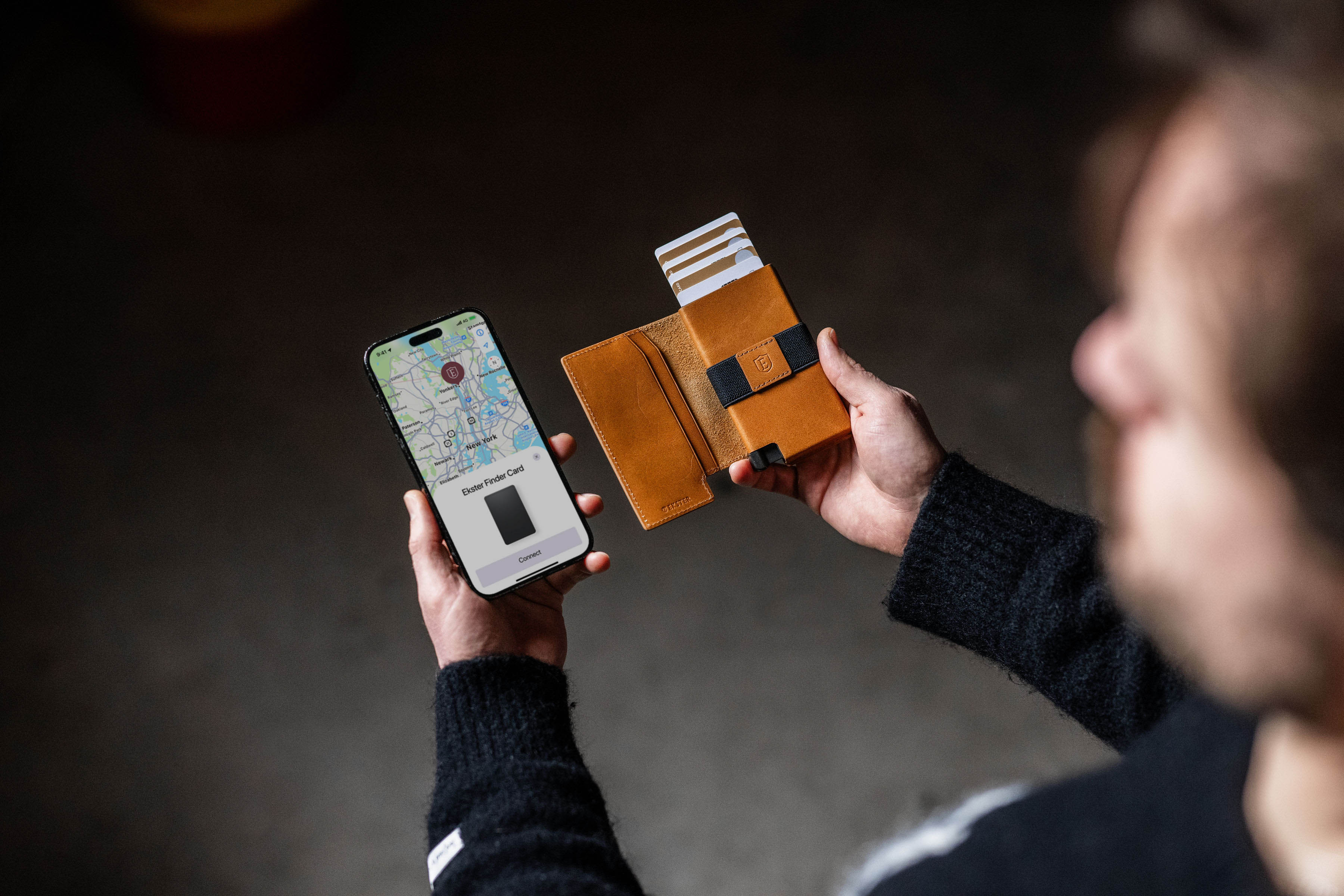 Person holding a smartphone with a map and a brown wallet with cards.