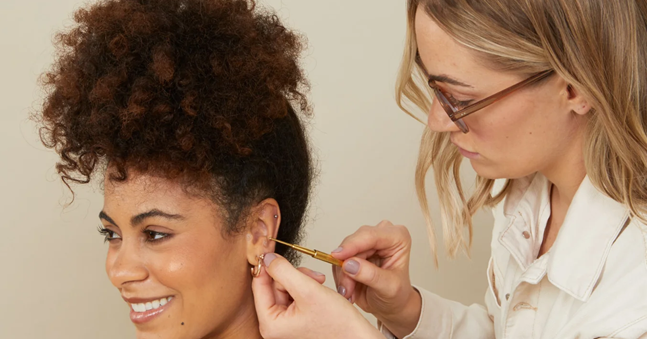 Person inserting an earring into another person's ear.