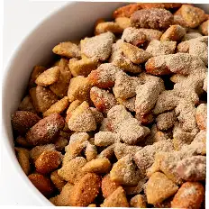 A close-up of a white bowl filled with dry, powdered kibble.