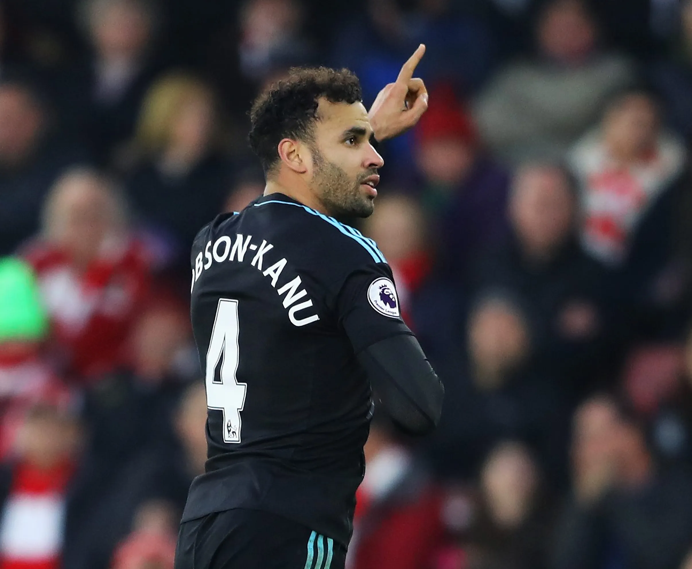 Soccer player Hal Robson-Kanu, wearing the number 4 jersey, points a finger in the air.