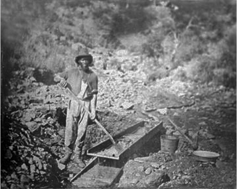 A person panning for gold in a rocky outdoor setting.