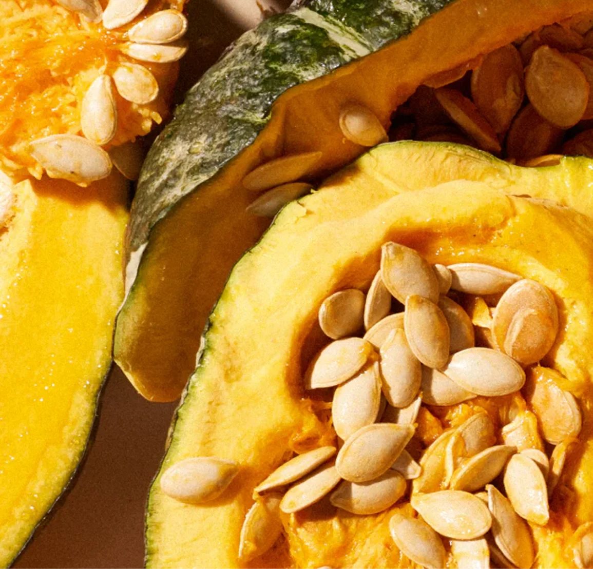 A close-up of a cut open green squash showing its bright yellow flesh and seeds.