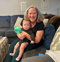 A person holding a baby seated on a couch in a living room.