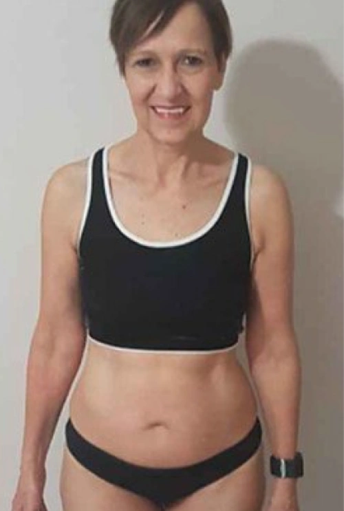 Woman wearing a black sports bra and black underwear, standing against a white background.