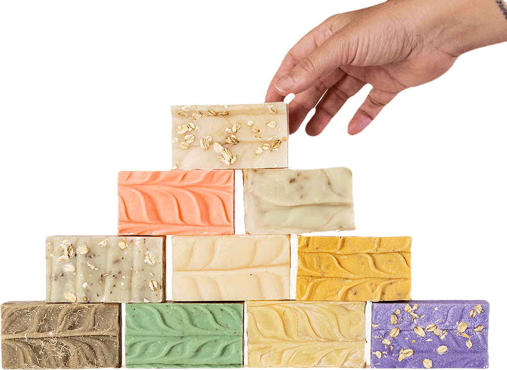 Hand arranging colorful soap bars in a pyramid shape.
