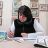 Person drawing at a desk with colorful art on the wall.