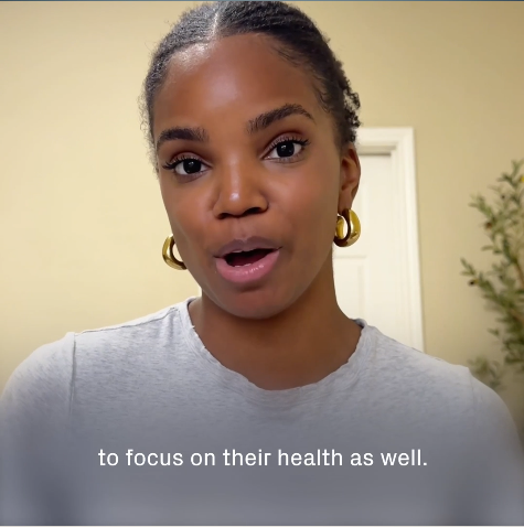 A close-up of a Black woman with gold hoop earrings and a gray t-shirt speaking.