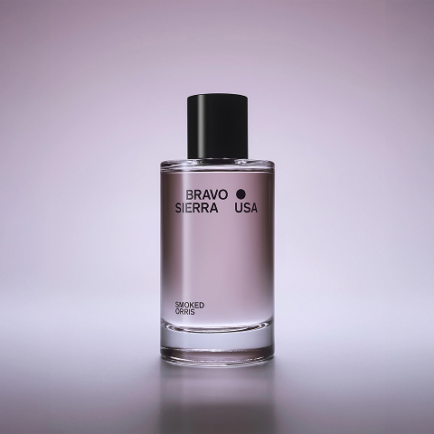 A clear glass bottle of Bravo Sierra USA Smoked Orris fragrance with a black cap on a purple background.