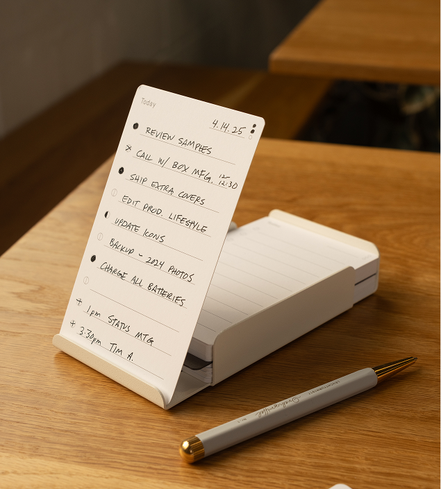A to-do list on a wooden desk with a pen beside it.