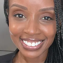 A close-up headshot of a smiling Black woman with braided hair, looking at the camera.