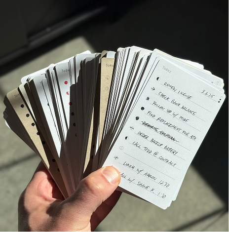 Hand holding a stack of index cards with handwritten notes.