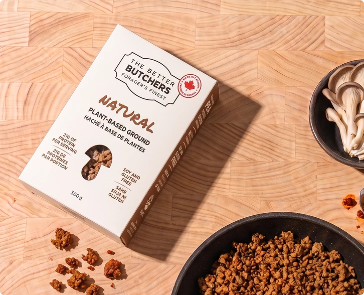 A box of The Better Butchers plant-based ground on a cutting board with the cooked product.