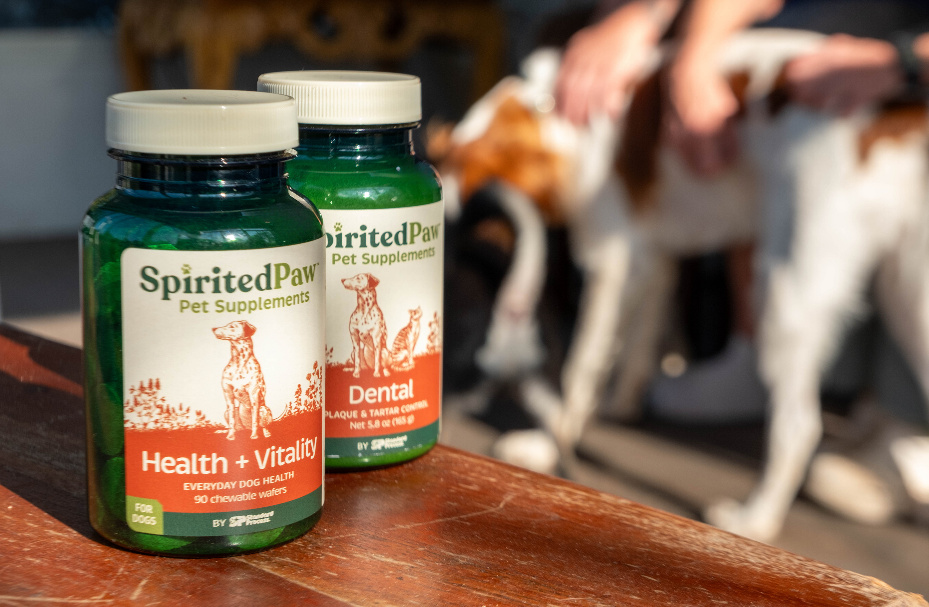 Two bottles of Spirited Paw pet supplements on a wooden surface.