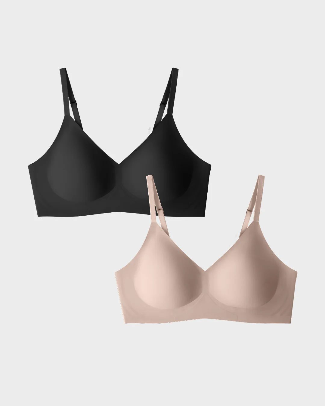 Two bras, one black and one beige, on a plain background.