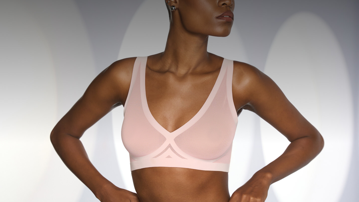 Person wearing a light pink sports bra against a neutral background.