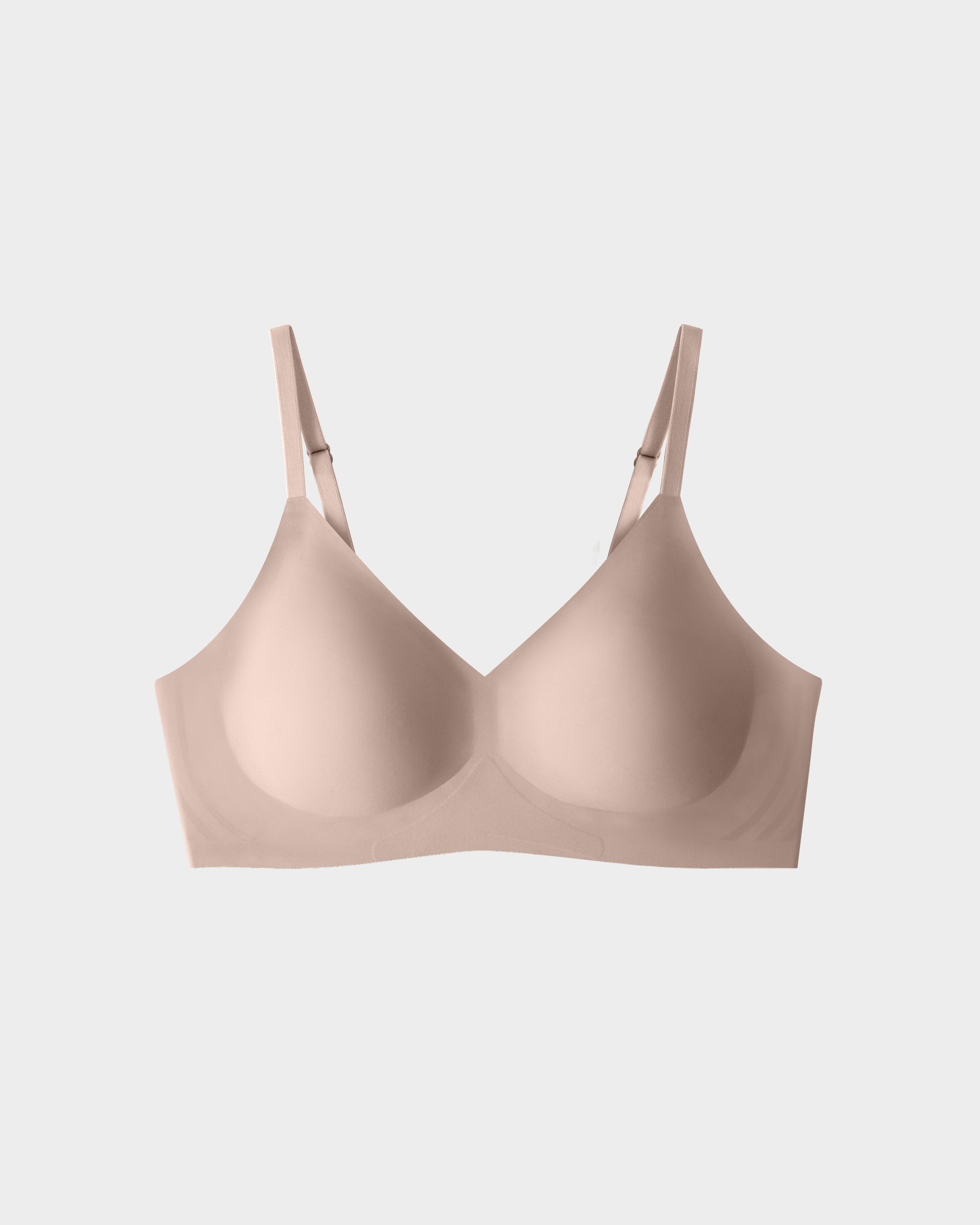 Nude-colored, seamless bra with adjustable straps displayed on a neutral background.