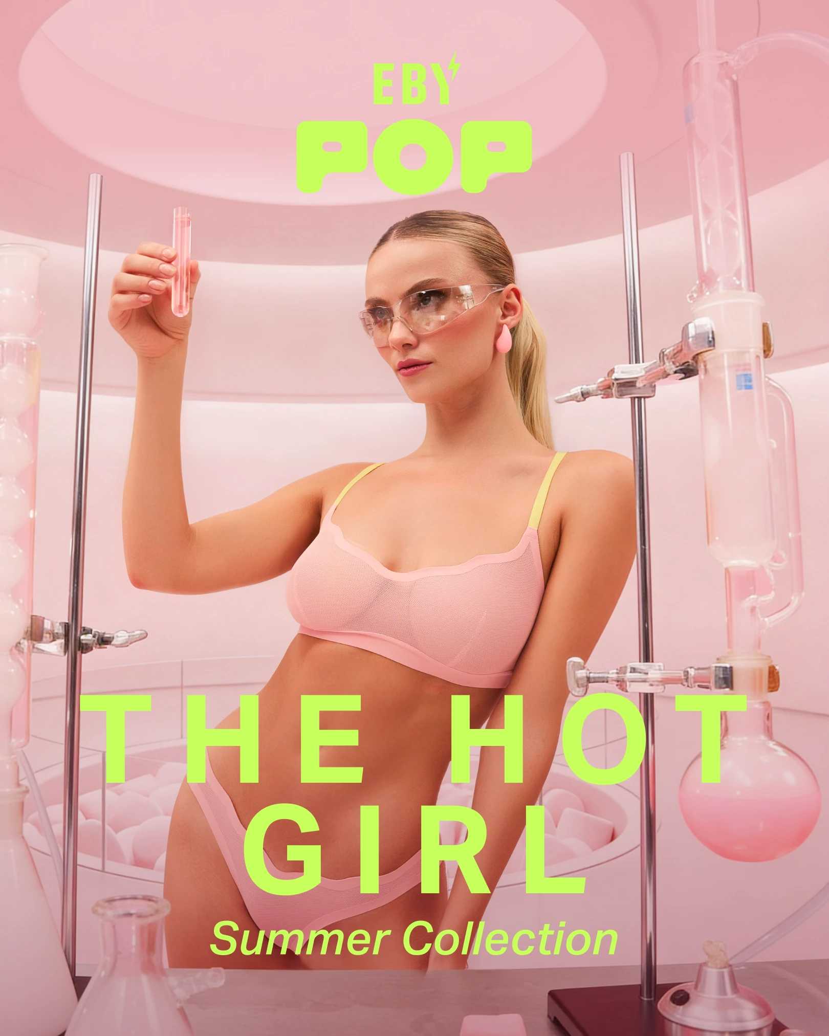 A woman in a pink bra and safety glasses holds a test tube in a pink laboratory setting.