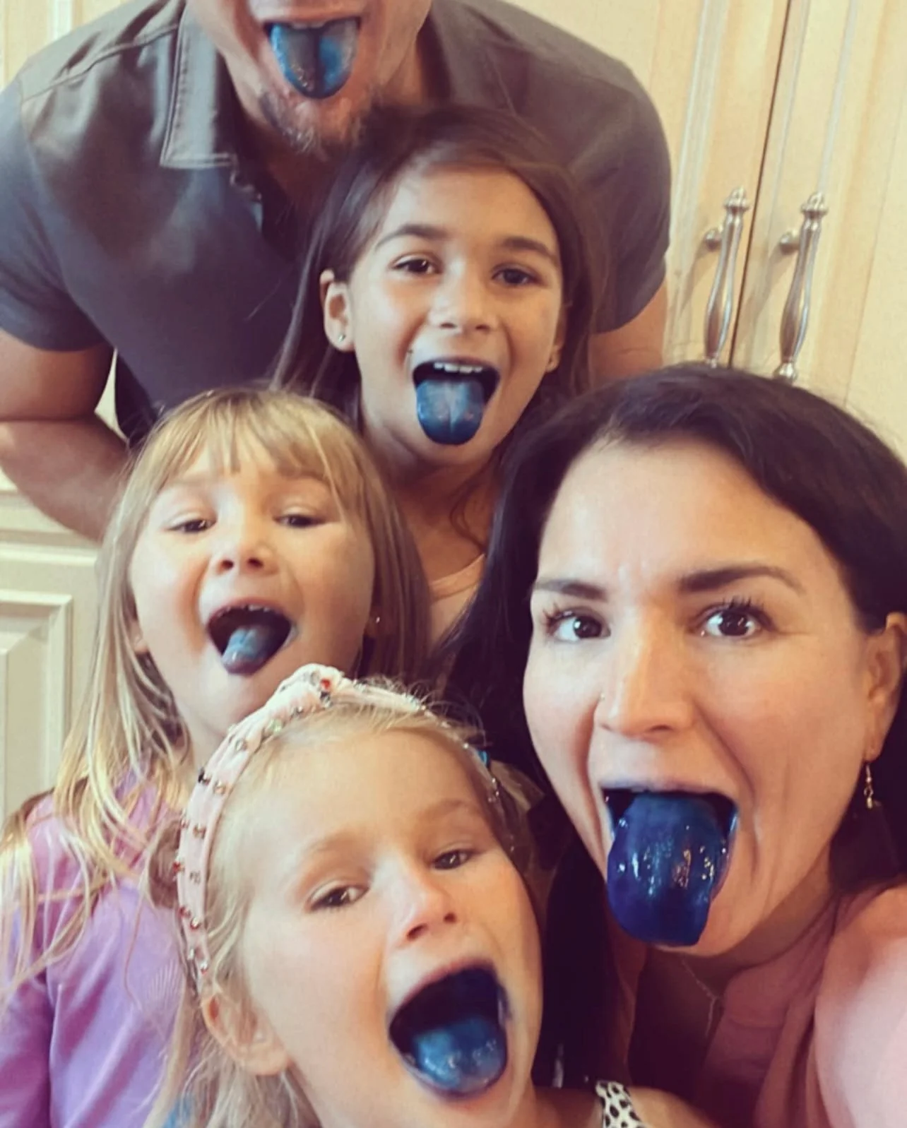 Group of people showing blue tongues, smiling at the camera.