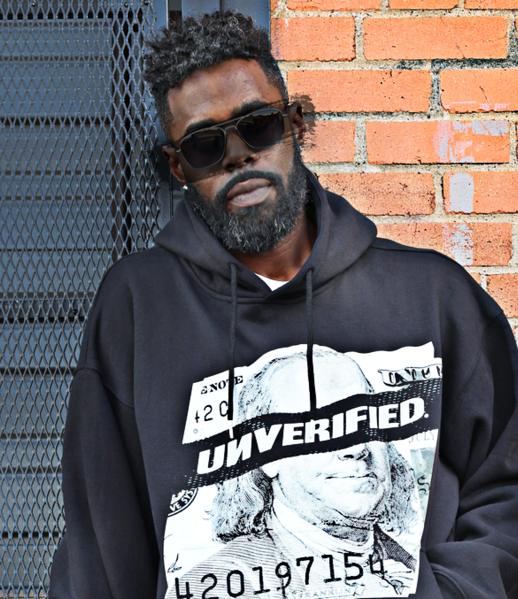 Individual in sunglasses wearing a hoodie with 'UNVERIFIED' text design.