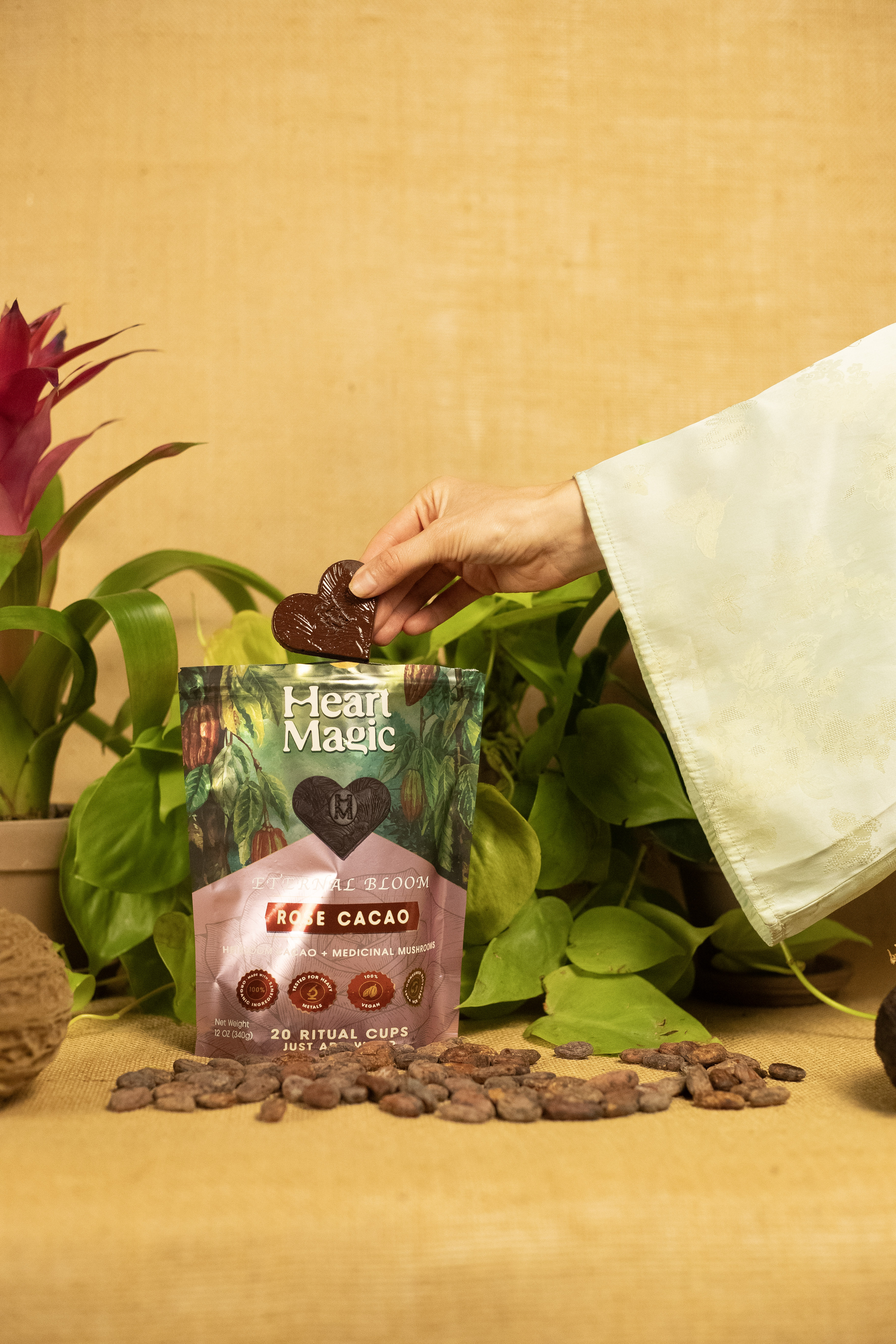 Hand holding heart-shaped chocolate above Heart Magic cacao package.