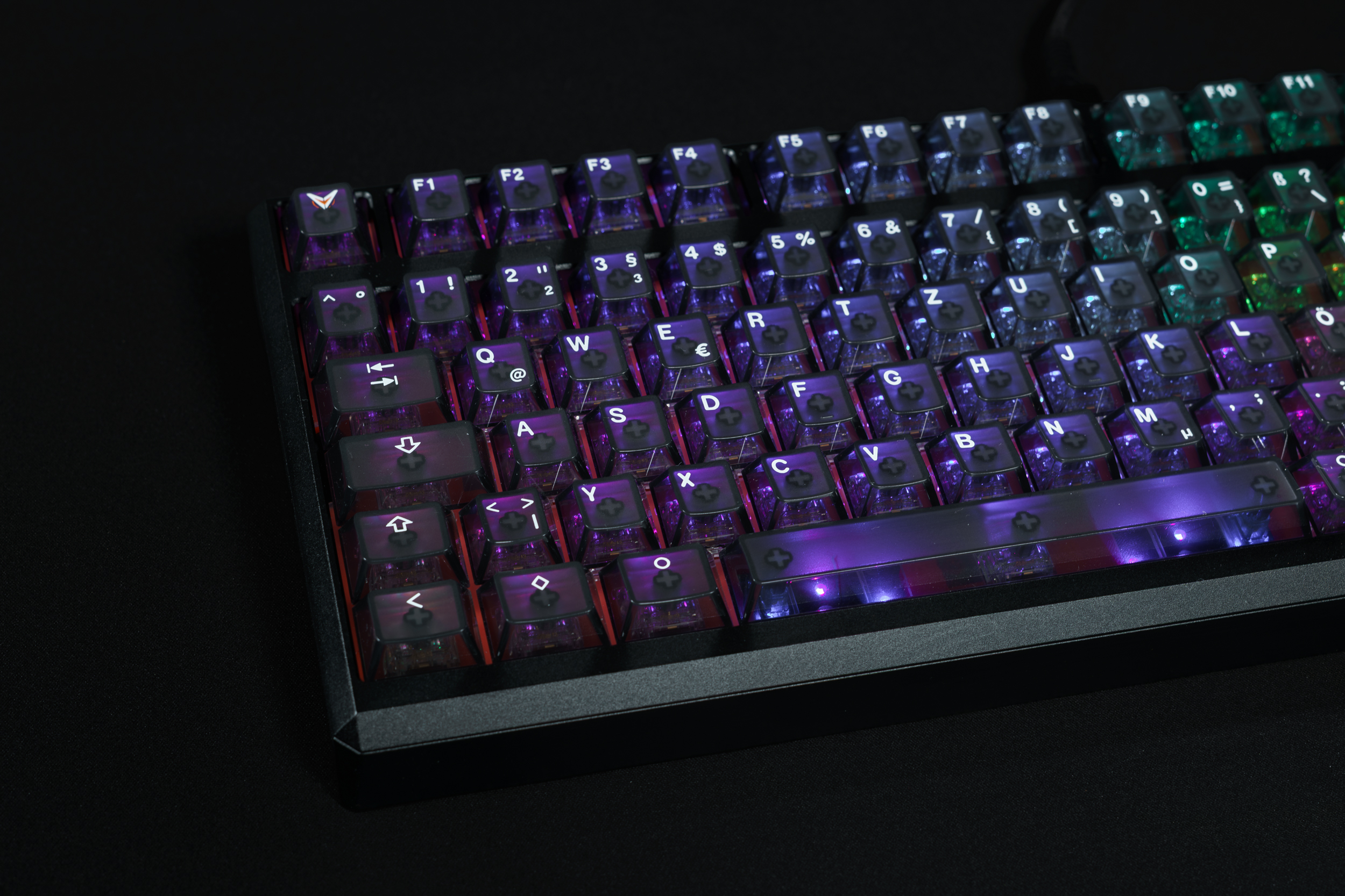 A close-up of a backlit mechanical keyboard with translucent purple keycaps on a black surface.