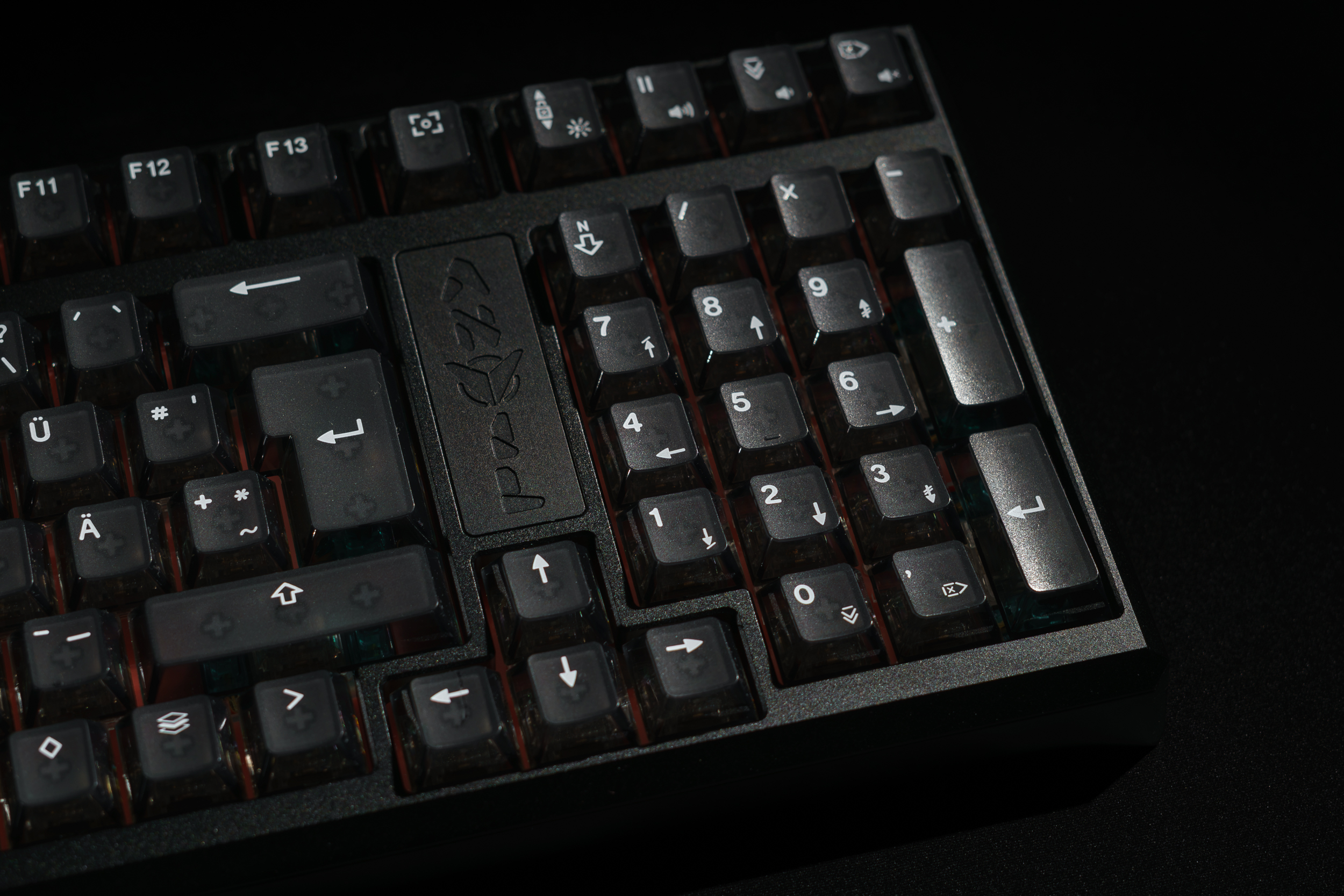 A close-up shot of a black mechanical keyboard with translucent keycaps on a dark surface.