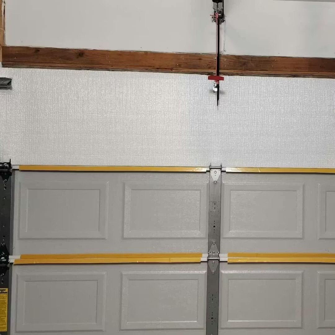 The interior view of a gray paneled garage door with yellow tape on the panel edges.