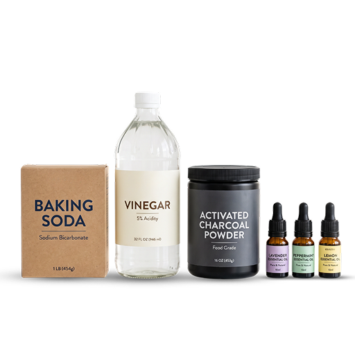 A box of baking soda, a bottle of vinegar, activated charcoal powder, and three bottles of essential oil.