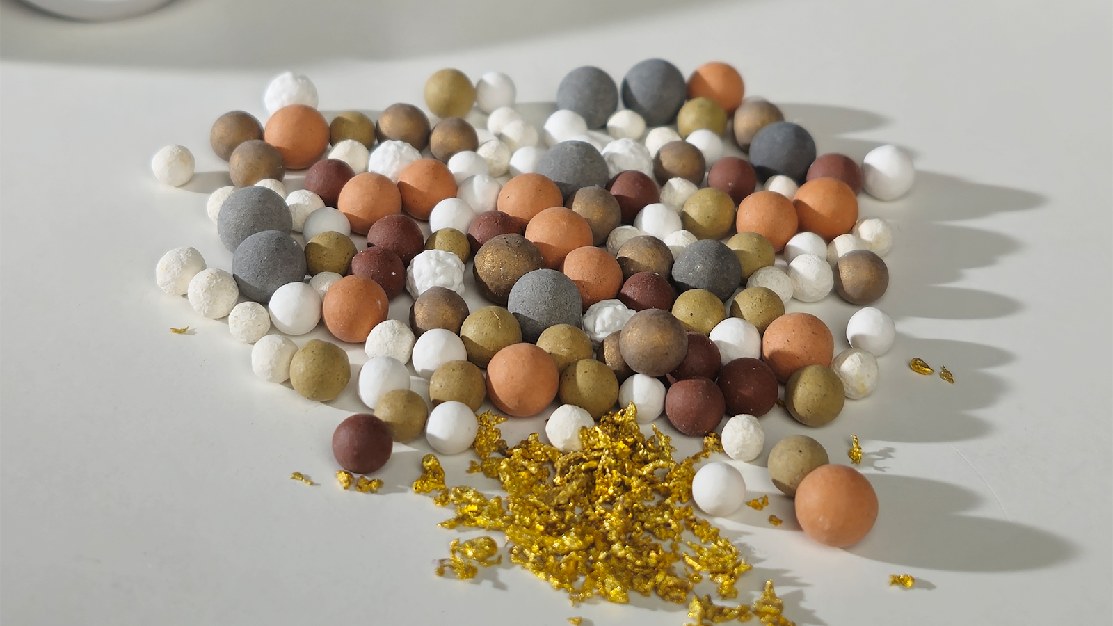 Assorted colored balls and gold flakes on a white surface.
