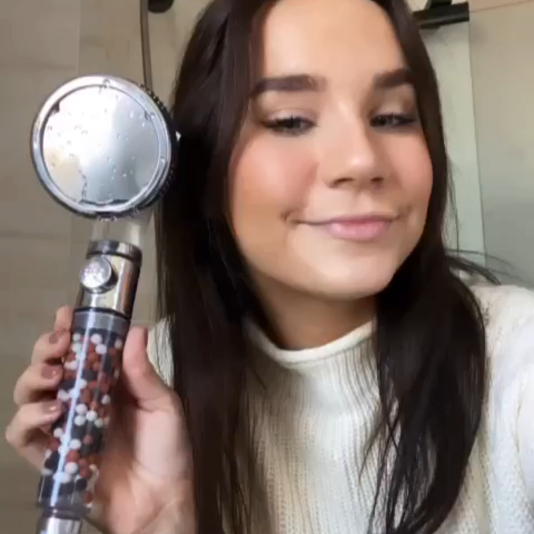 Person holding a shower head with mineral beads inside.