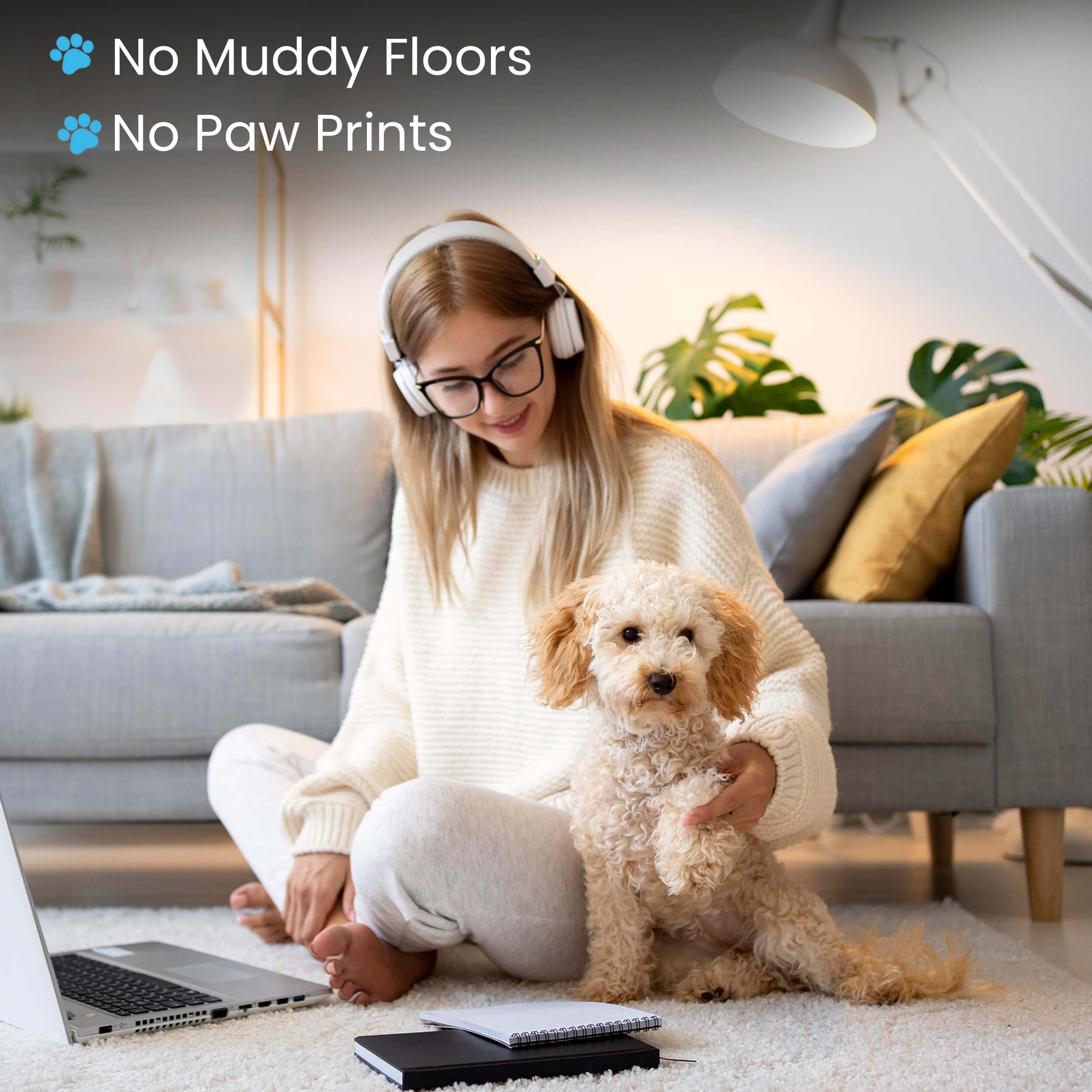Woman with headphones holding a curly-haired dog in a cozy living room.