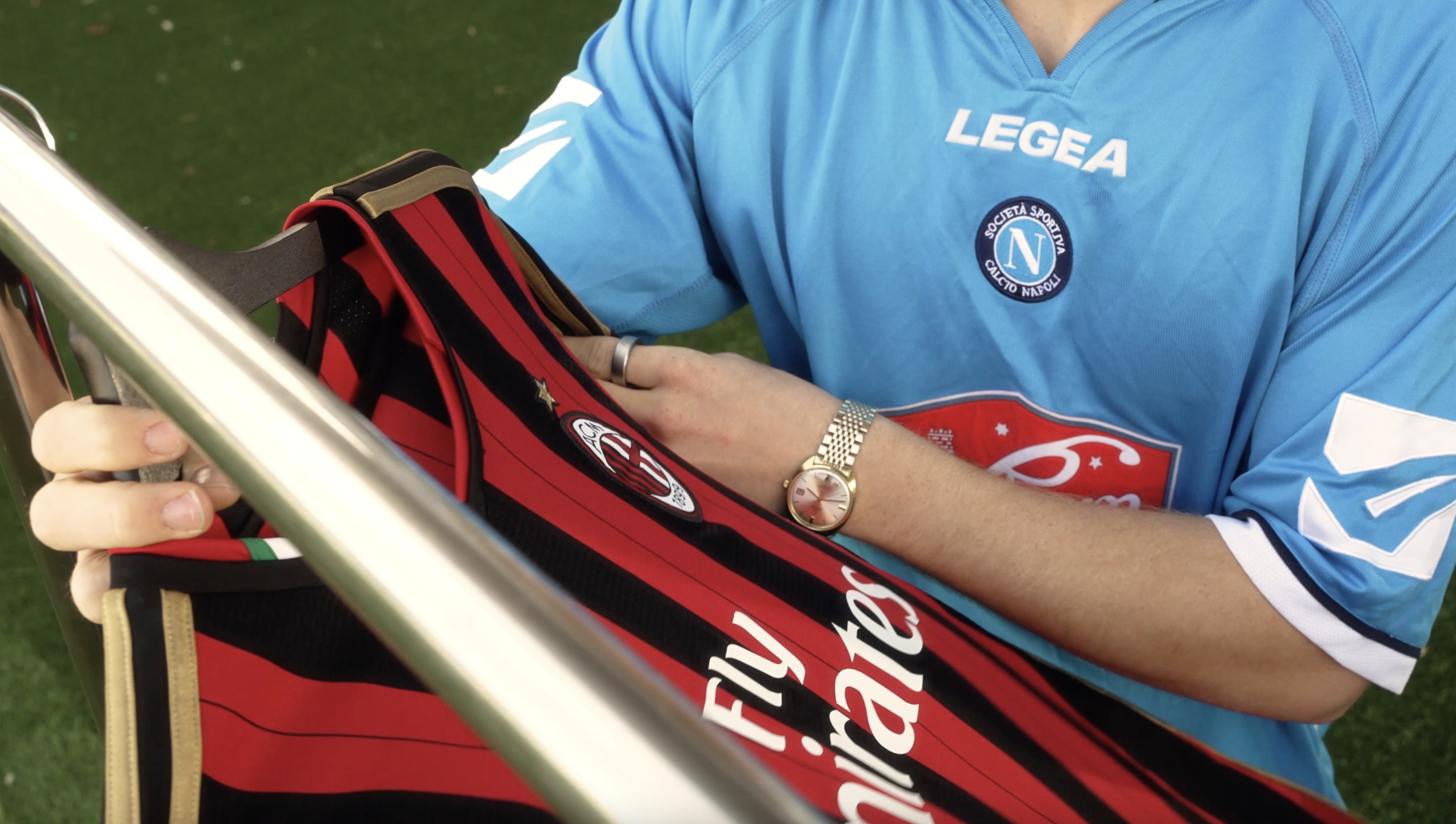Person in blue jersey holding a red and black striped football shirt.