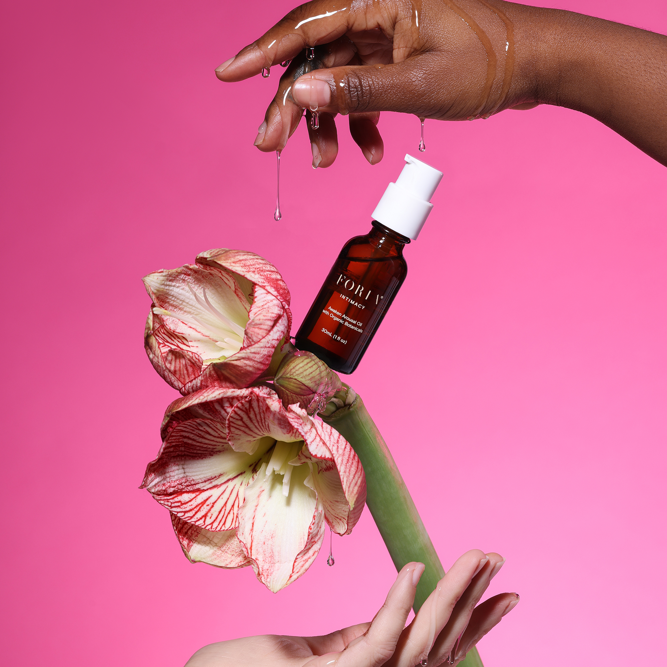 Hands holding a flower with a bottle against a pink background.