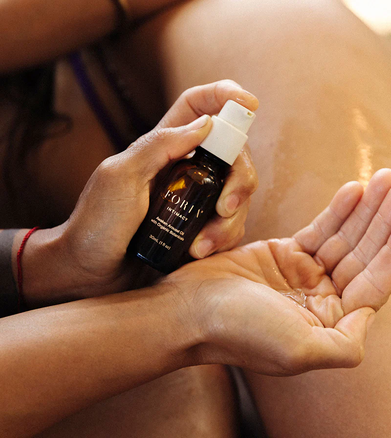 A hand holding a bottle of Foria CBD arousal oil.