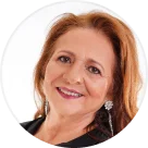 Smiling woman with red hair and earrings against a white background.