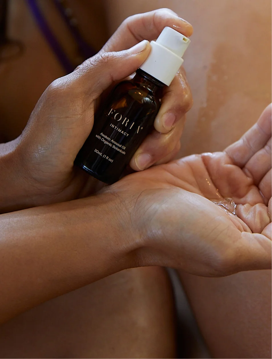 Hands holding a small bottle, dispensing liquid into a palm.