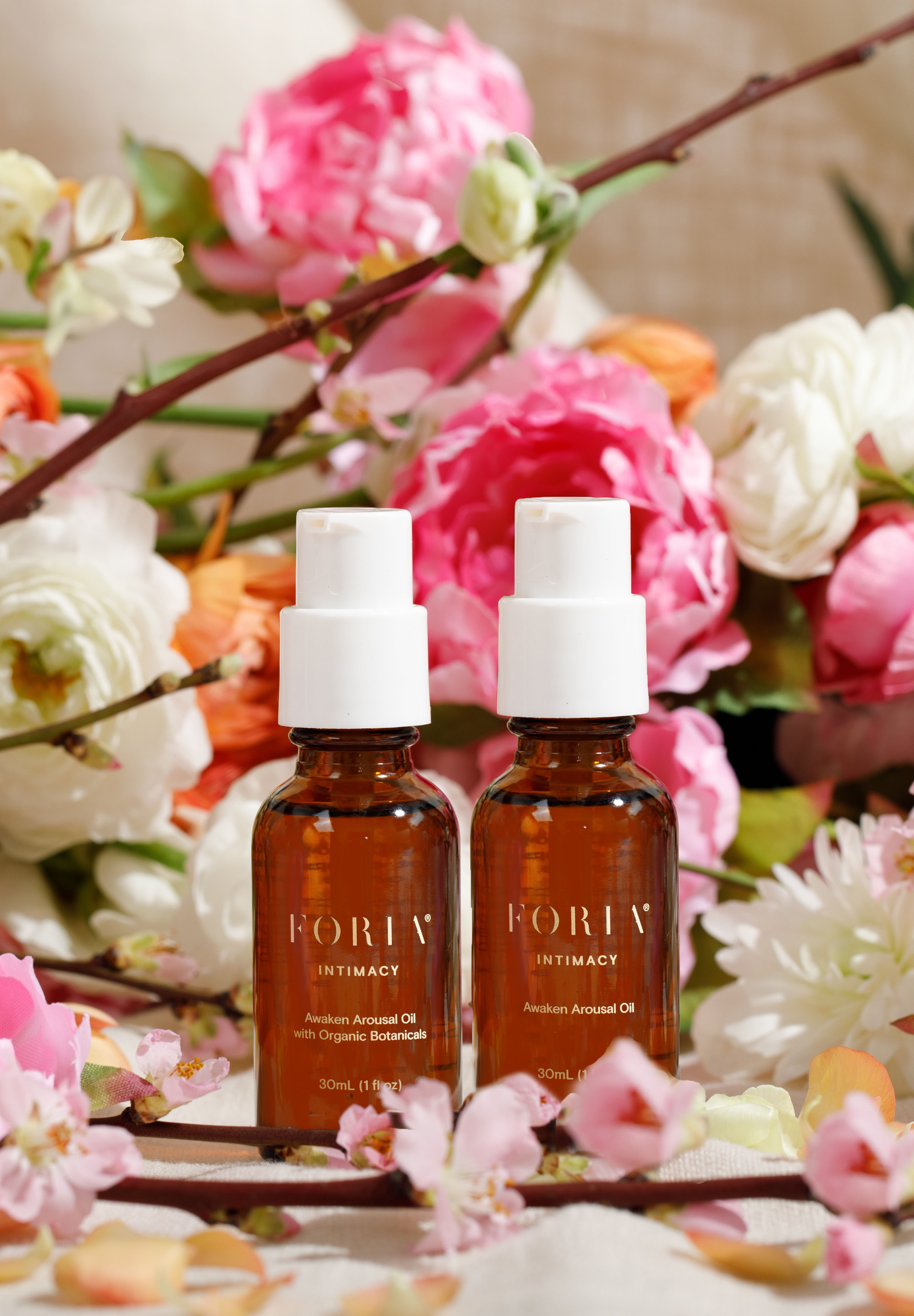 Two bottles of oil surrounded by colorful flowers.