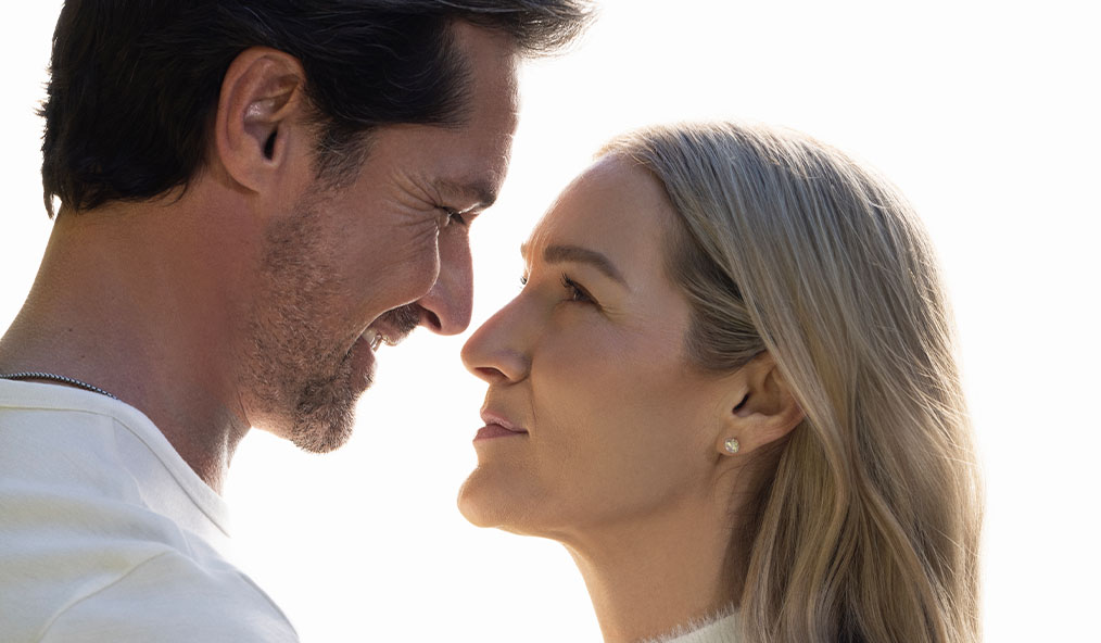 A man and woman facing each other closely, smiling.