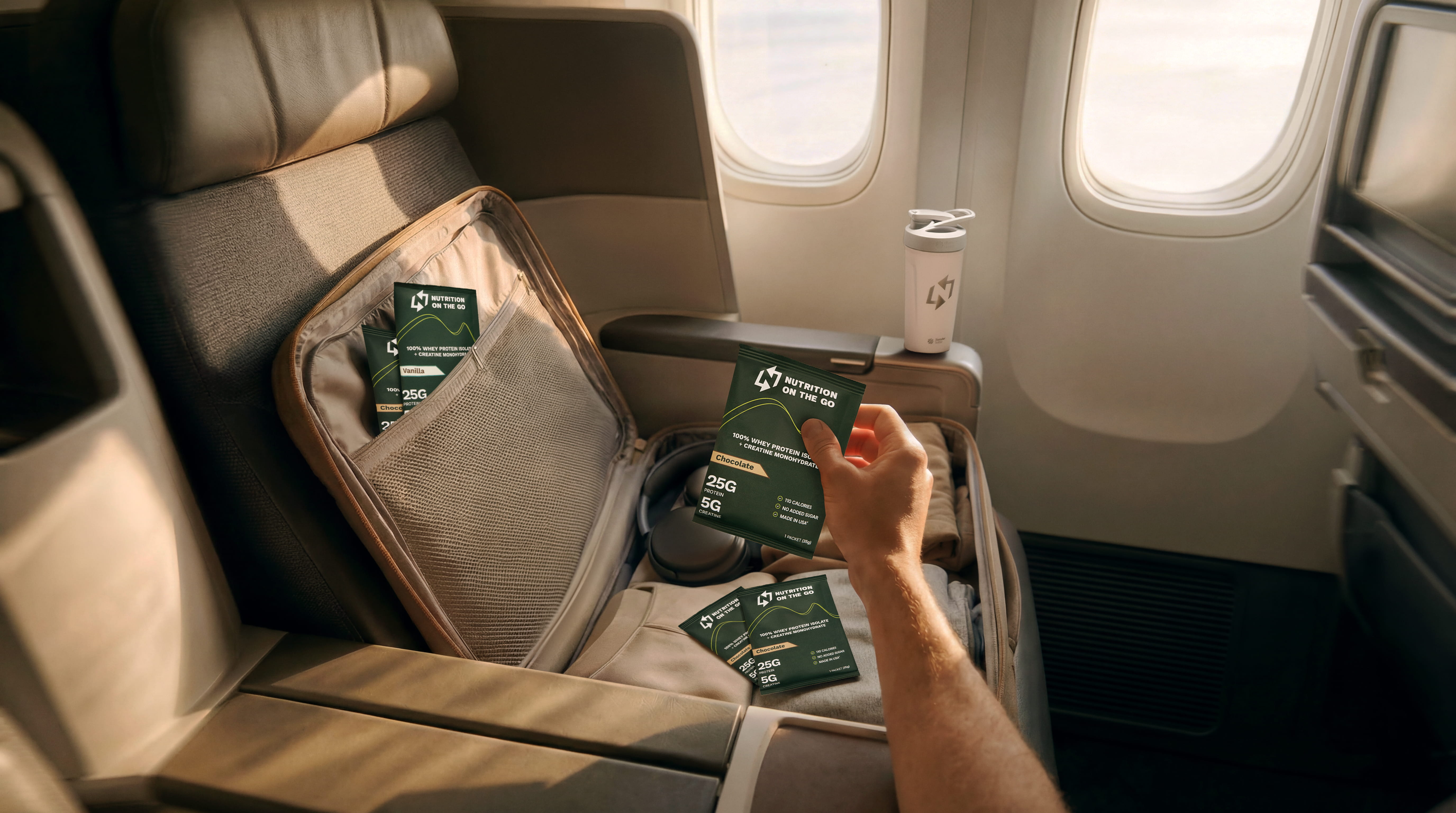 A person on an airplane holds a Nutrition on the Go packet over an open suitcase.