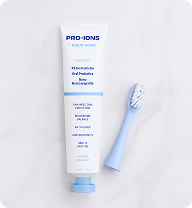 White toothpaste tube with blue cap and blue toothbrush on a marble surface.