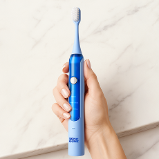 Hand holding a blue electric toothbrush against a marble background.