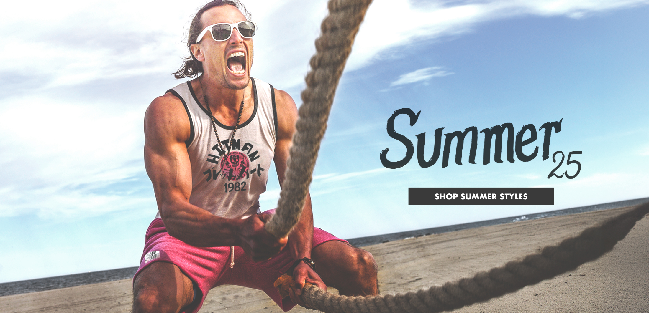 Man exercising with ropes on a beach, wearing sunglasses and a tank top.