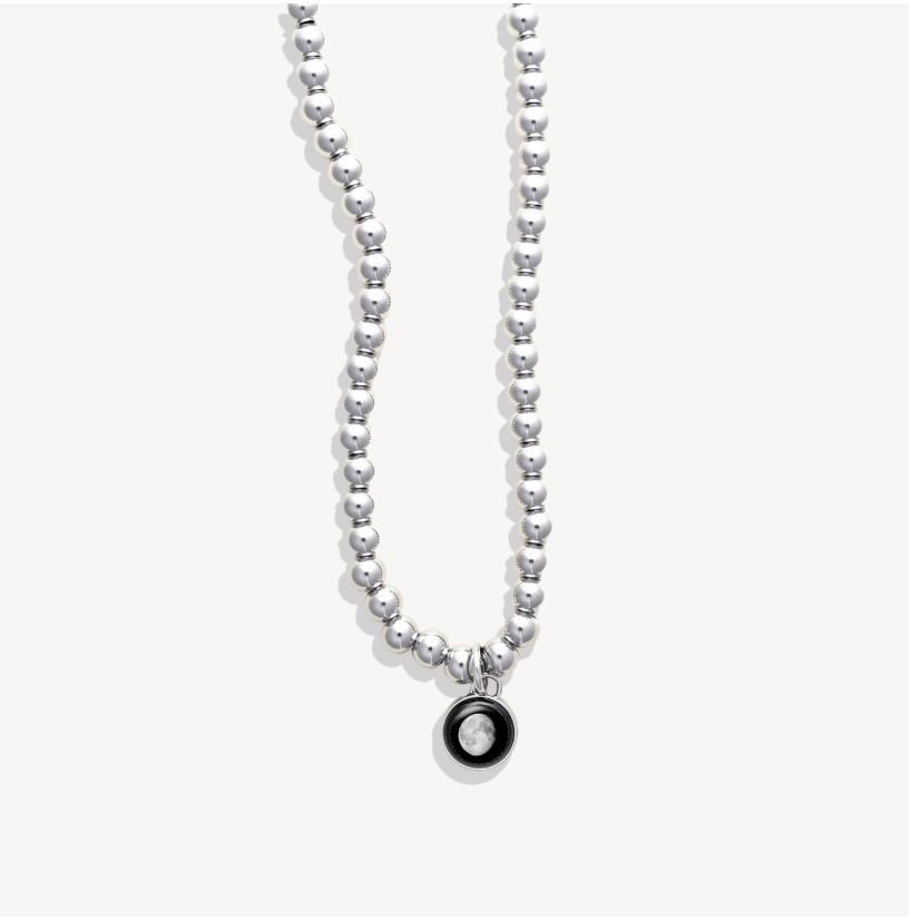Silver beaded necklace with a round pendant featuring a moon image.