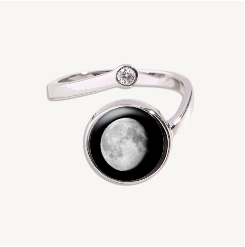 Silver ring with a moon design and a small gemstone.