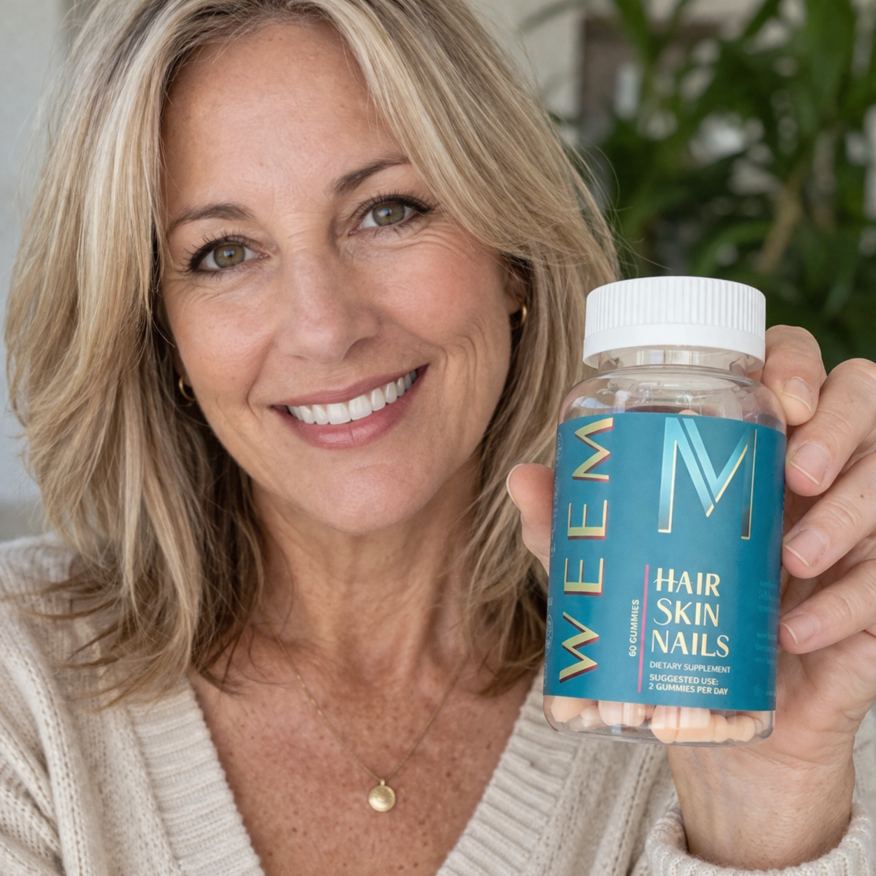 A smiling woman with blonde hair holds up a bottle of WEEM Hair Skin Nails gummies.