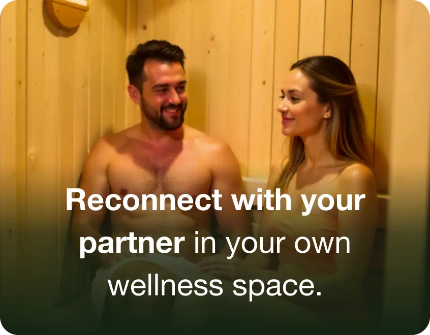 Two people sitting in a wooden sauna, smiling at each other.