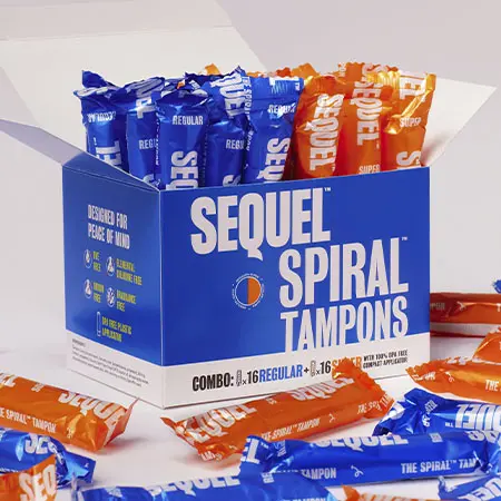 An open box of Sequel Spiral Tampons with blue and orange wrapped tampons inside and around it.