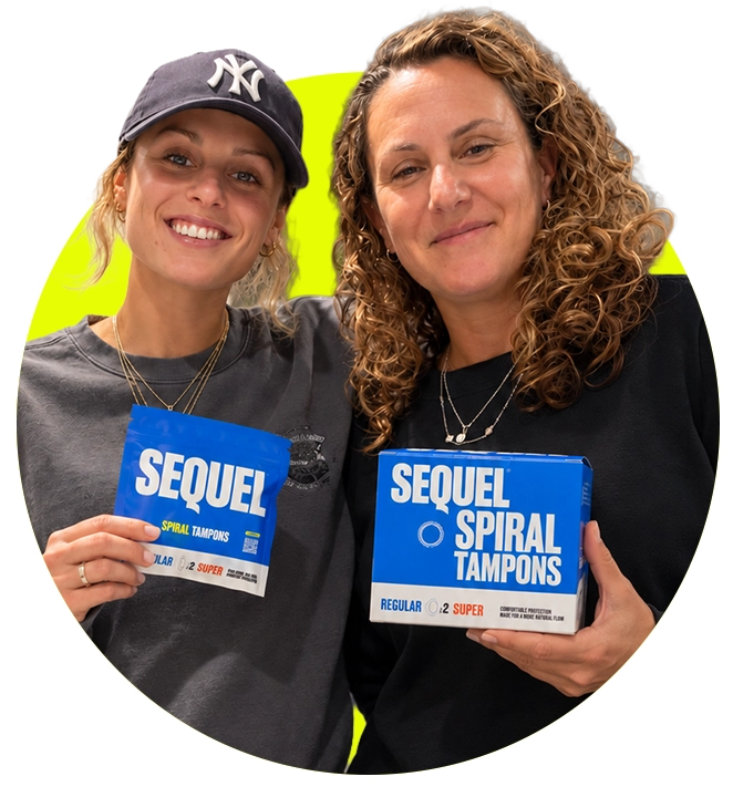 Two smiling women hold up packages of Sequel Spiral Tampons against a bright green background.