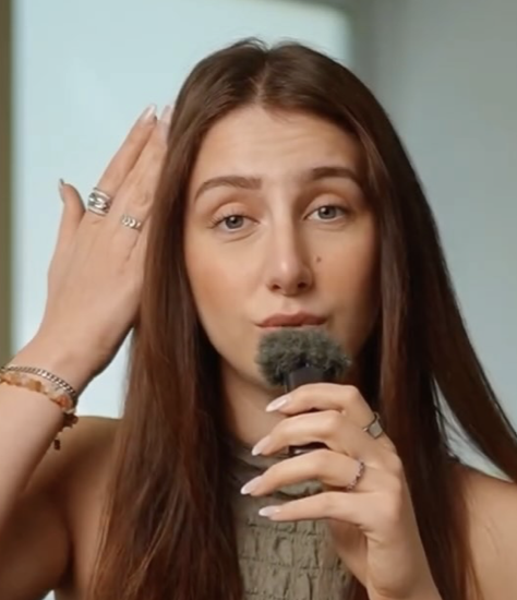 Person holding a microphone, gesturing with hand.