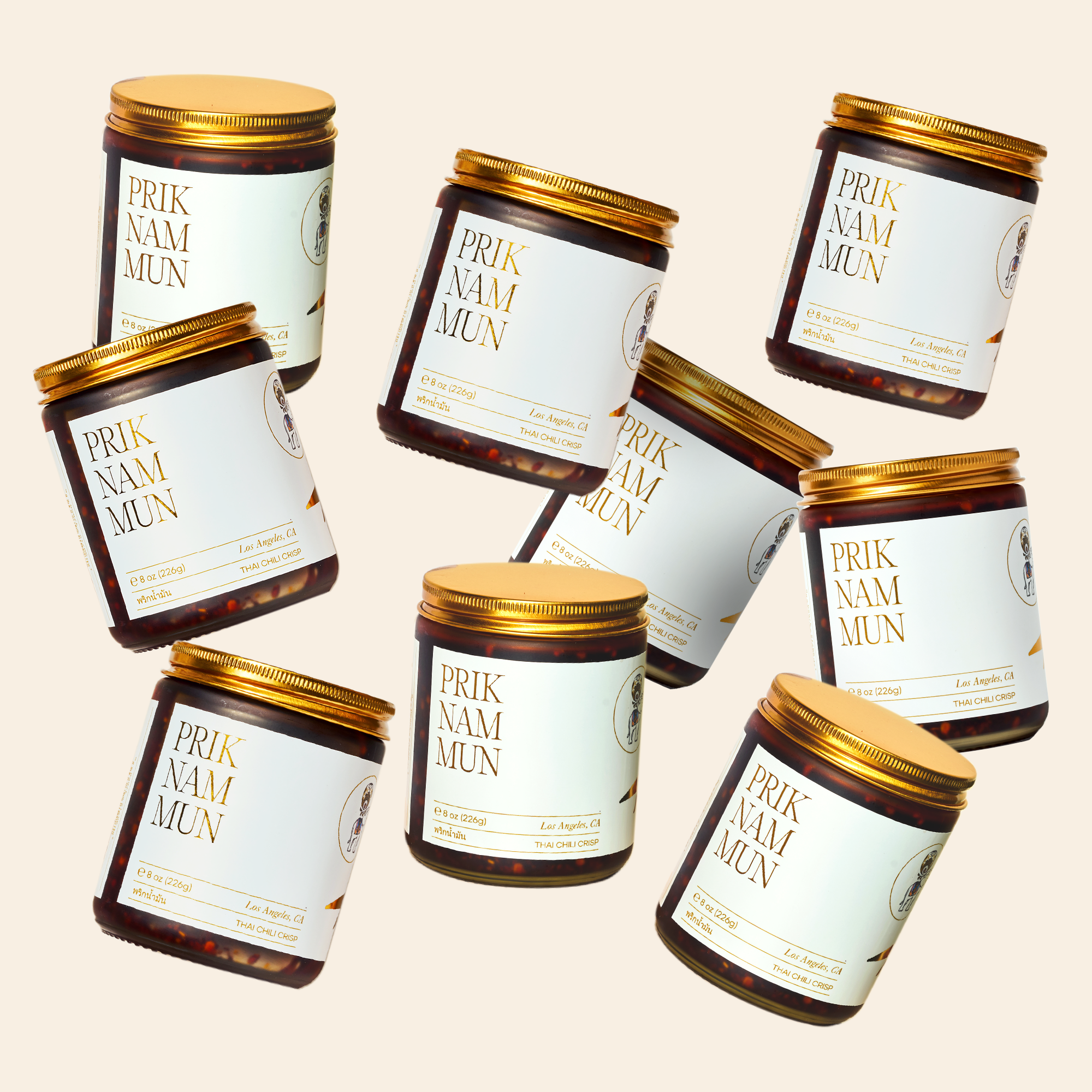 Multiple jars of Prik Nam Mun Thai Chili Crisp are scattered against a light-colored background.